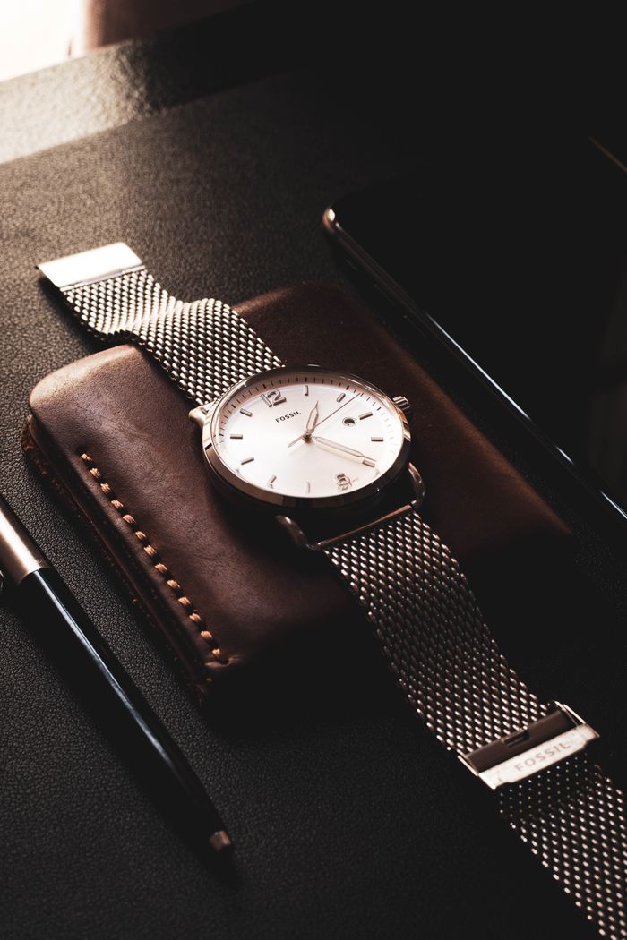 Close-up of a sophisticated wristwatch resting on a leather wallet, captured with a minimalistic touch.