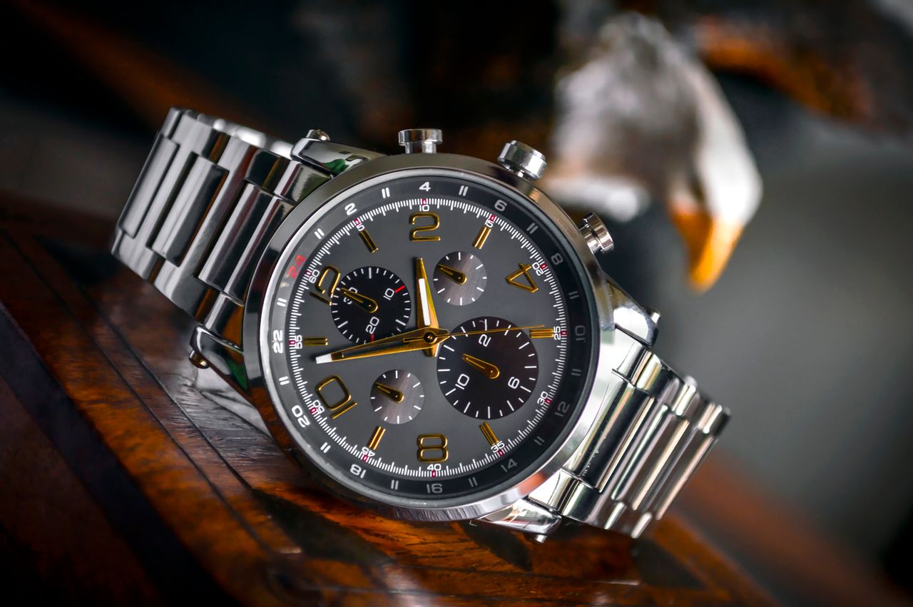 services-img Luxury wristwatch with stainless steel bracelet displayed elegantly on a wooden background.